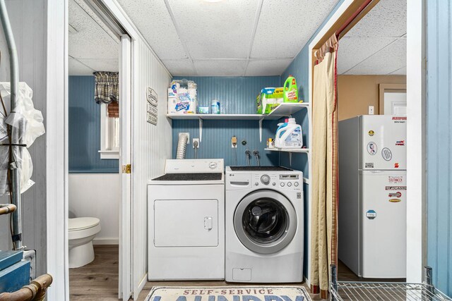 laundry room with laundry area, washing machine and dryer, and wood finished floors