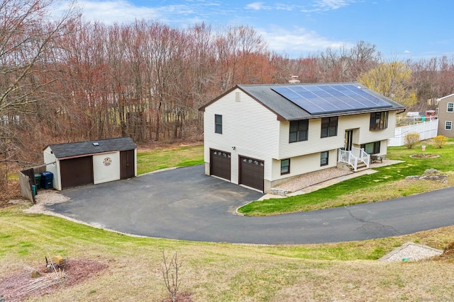 bi-level home with solar panels, an attached garage, fence, a front lawn, and driveway