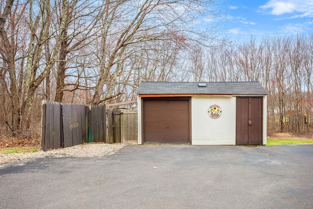 detached garage with aphalt driveway and fence