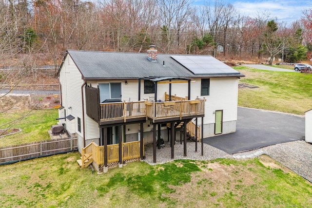 back of property featuring a deck, a yard, a patio area, a chimney, and fence