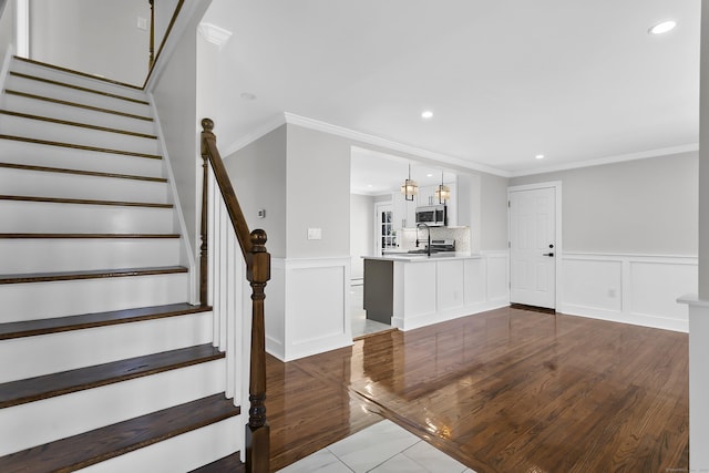 interior space featuring crown molding, recessed lighting, and a wainscoted wall