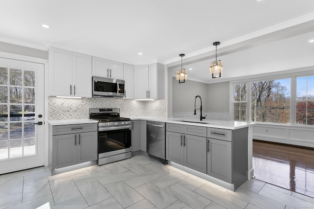 kitchen featuring a peninsula, plenty of natural light, a sink, gray cabinetry, and stainless steel appliances