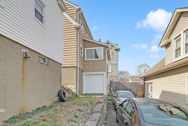 15 Smith St, Danbury, CT 06810 - view of side of property featuring an attached garage, fence, a wall unit AC, and driveway