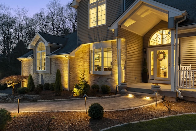 exterior entry at dusk featuring brick siding