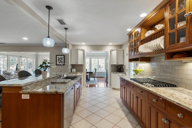 kitchen with visible vents, tasteful backsplash, a sink, glass insert cabinets, and stainless steel appliances