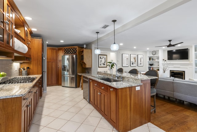 kitchen featuring visible vents, appliances with stainless steel finishes, a sink, light tile patterned floors, and a breakfast bar