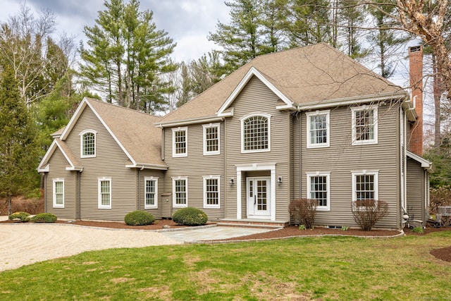 colonial home featuring a patio area, a shingled roof, a chimney, and a front lawn
