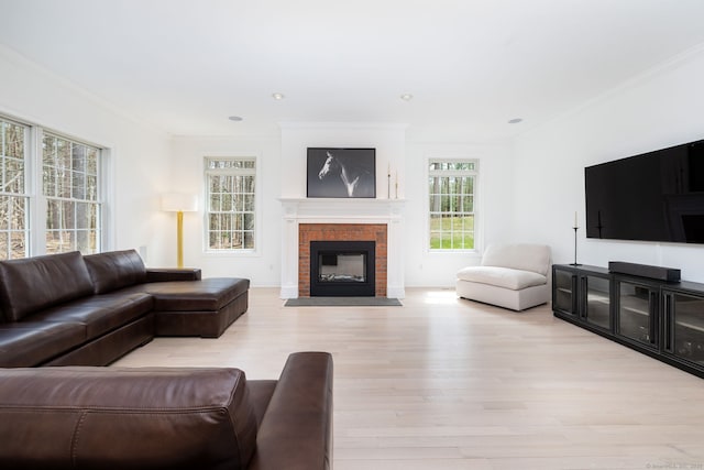 living room featuring a fireplace with flush hearth, crown molding, recessed lighting, and light wood-type flooring