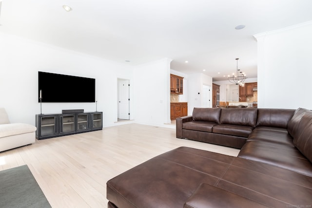 living room featuring a chandelier, light wood finished floors, ornamental molding, and recessed lighting