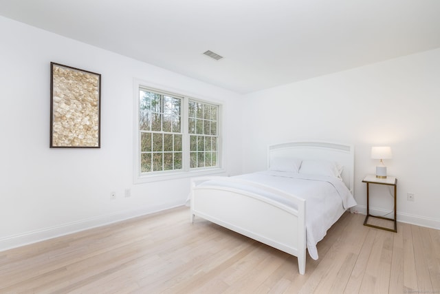 bedroom with visible vents, light wood-style flooring, and baseboards