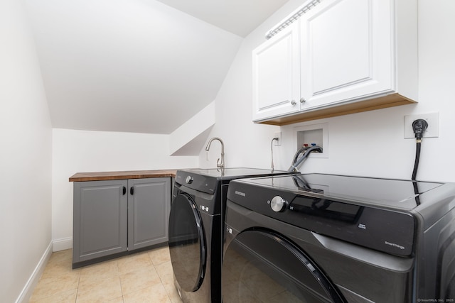 clothes washing area featuring cabinet space, light tile patterned floors, baseboards, and washer and dryer