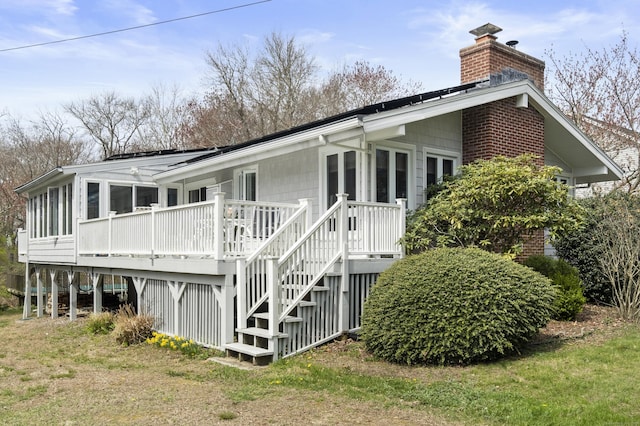 33 Cottage Ln, East Lyme, CT 06357 - rear view of house featuring stairs, a chimney, a sunroom, and a deck