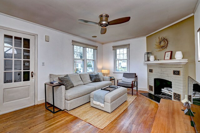 living area featuring hardwood / wood-style flooring, a ceiling fan, ornamental molding, a fireplace, and baseboards