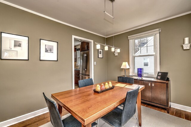 dining area featuring dark wood finished floors, baseboards, and ornamental molding