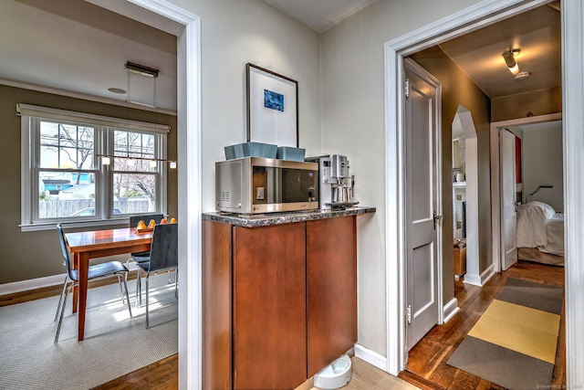 bar area featuring wood finished floors, baseboards, and stainless steel microwave