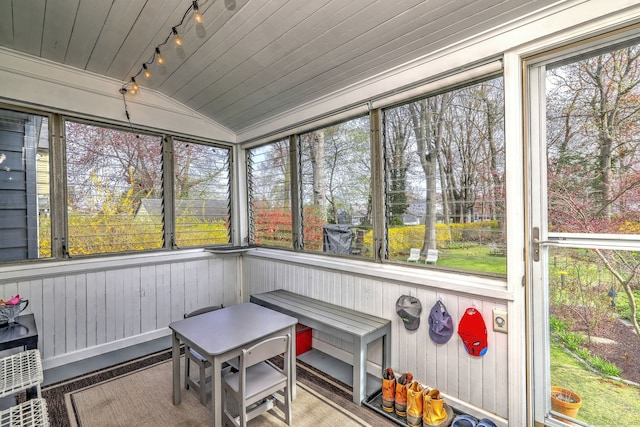 sunroom / solarium featuring track lighting and vaulted ceiling