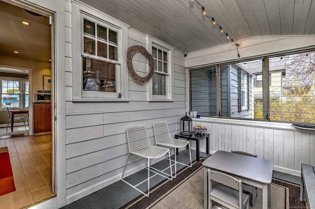 sunroom featuring rail lighting and lofted ceiling