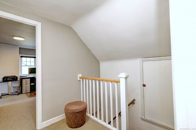 corridor with an upstairs landing, carpet, lofted ceiling, and baseboards