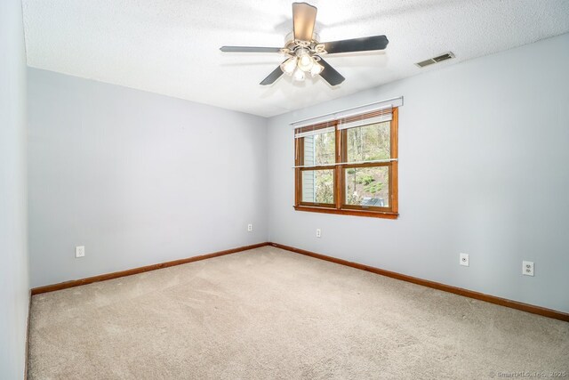 carpeted empty room featuring baseboards, a ceiling fan, and visible vents