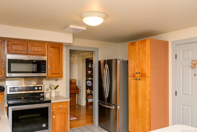 kitchen featuring decorative backsplash, brown cabinets, stainless steel appliances, and light countertops