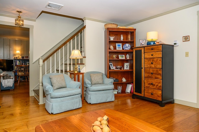 sitting room with stairway, visible vents, hardwood / wood-style floors, and ornamental molding