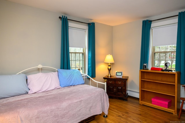 bedroom with baseboard heating and wood finished floors