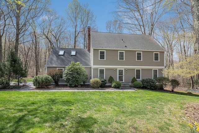 colonial inspired home with a chimney and a front yard
