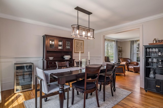 dining area featuring ornamental molding, light wood finished floors, and wine cooler