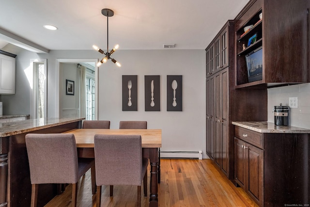 dining space with a baseboard radiator, a notable chandelier, light wood finished floors, and visible vents