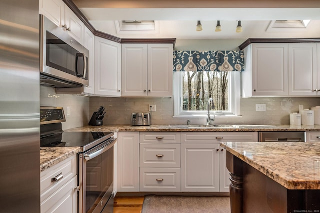 kitchen with appliances with stainless steel finishes, white cabinets, and backsplash