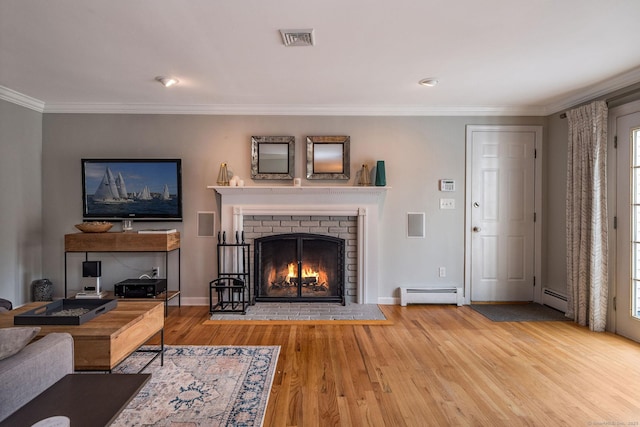 living room with baseboard heating, a brick fireplace, wood finished floors, and visible vents