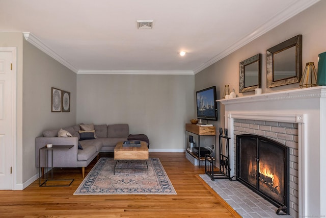 living room featuring visible vents, ornamental molding, wood finished floors, and a fireplace
