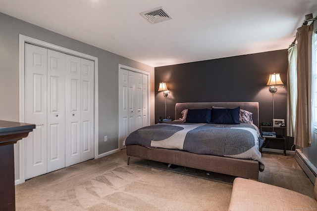 carpeted bedroom featuring multiple closets, baseboards, and visible vents