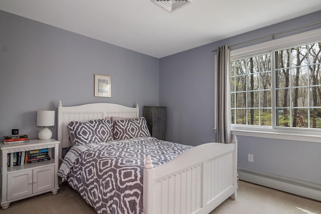 bedroom with visible vents, a baseboard heating unit, and carpet