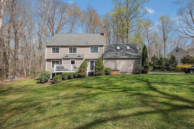 back of property with a lawn, a chimney, and a deck