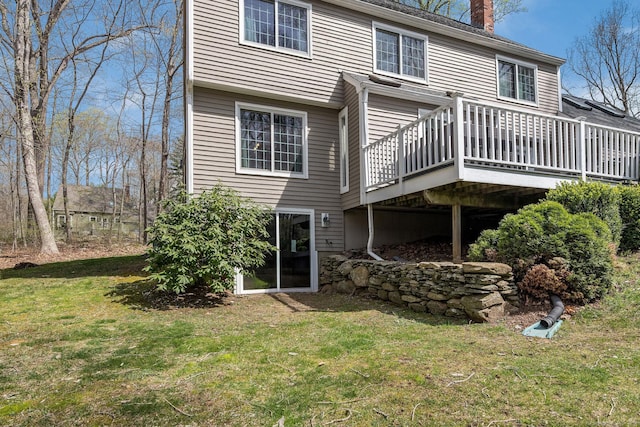 back of property with a lawn, a chimney, and a wooden deck