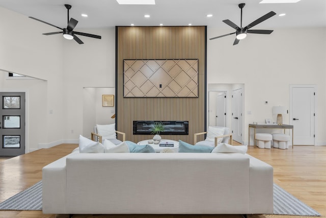 35 Bayberry Ln, Guilford, CT 06437 - living room featuring a glass covered fireplace, a towering ceiling, a skylight, and a ceiling fan