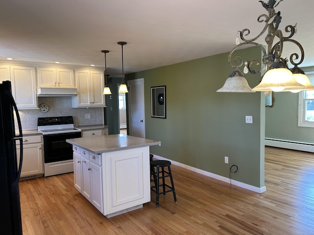 kitchen with freestanding refrigerator, light wood-type flooring, white cabinets, under cabinet range hood, and range with electric cooktop