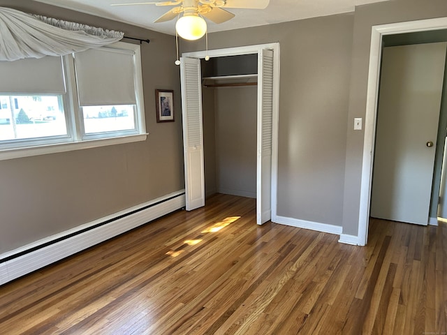 unfurnished bedroom with a closet, baseboards, wood finished floors, and baseboard heating