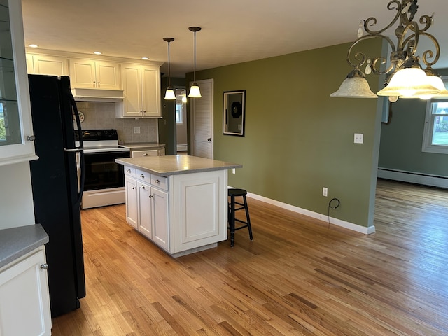 kitchen featuring freestanding refrigerator, white cabinetry, under cabinet range hood, electric stove, and a baseboard radiator