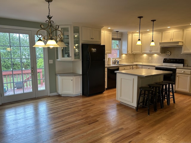 kitchen with under cabinet range hood, a sink, black appliances, and a healthy amount of sunlight