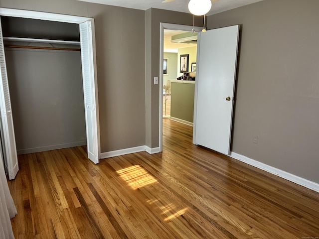 unfurnished bedroom featuring a closet, baseboards, and wood finished floors