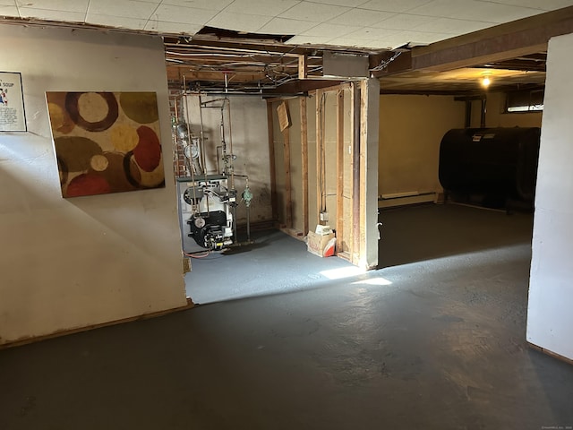 unfinished below grade area featuring a baseboard radiator, a heating unit, and heating fuel