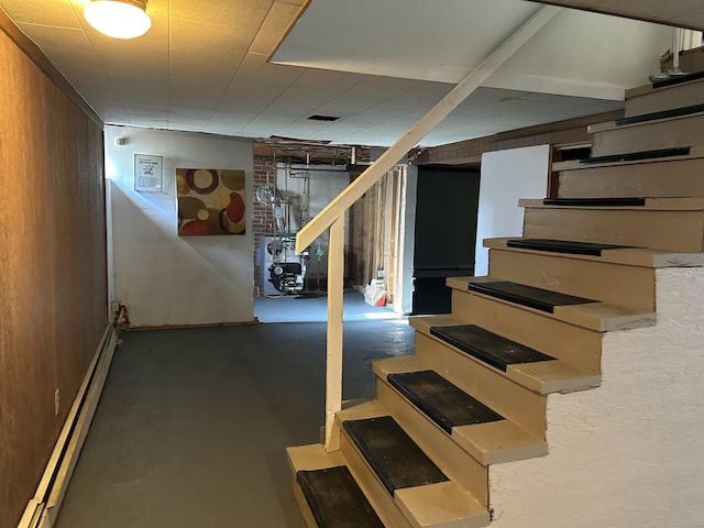 finished basement featuring stairway and baseboard heating