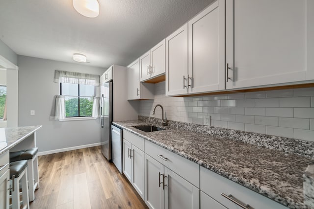 231 Heritage Vlg Unit C, Southbury, CT 06488 - kitchen with light wood-style floors, light stone countertops, appliances with stainless steel finishes, backsplash, and white cabinetry