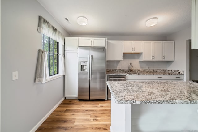 231 Heritage Vlg Unit C, Southbury, CT 06488 - kitchen featuring stainless steel appliances, light wood-type flooring, backsplash, white cabinets, and light stone counters