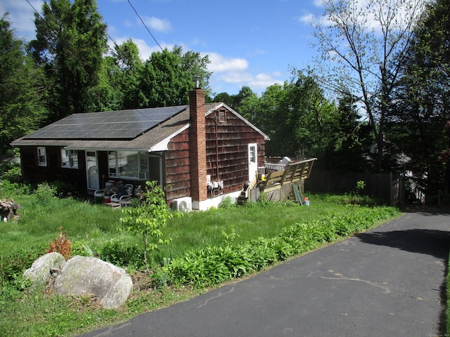 37 Foley Ave, Shelton, CT 06484 - view of property exterior with roof mounted solar panels, a chimney, and a shingled roof