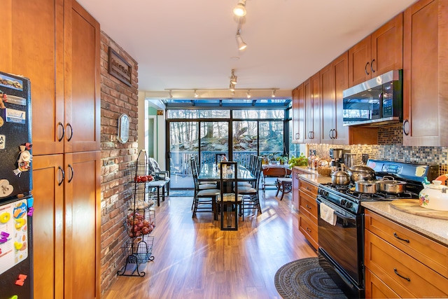 259 Weatherly Trl, Guilford, CT 06437 - kitchen with rail lighting, brown cabinets, light wood finished floors, stainless steel microwave, and black gas range oven