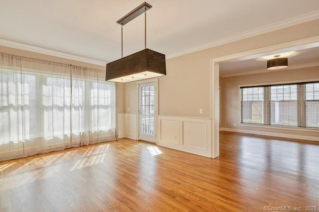 interior space featuring crown molding, wainscoting, and wood finished floors
