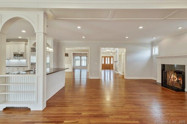 unfurnished living room featuring recessed lighting, a lit fireplace, crown molding, and wood finished floors